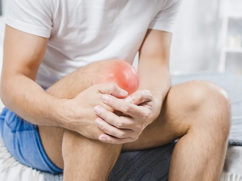 Man holding a painful knee, a common sign of knee osteoarthritis